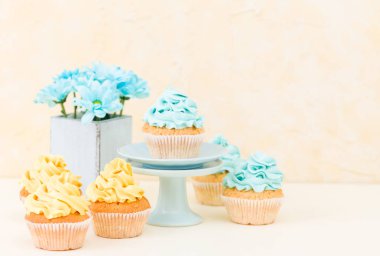 Tatlı mavi ve sarı buttercream dekorasyon ve mavi krizantem retro eski püskü şık vazoda ile cupcake.