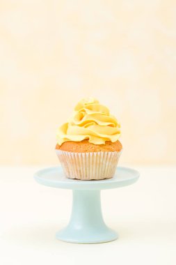Cupcake mavi sarı arka plan - pastel dikey afiş kürsüye üzerinde sarı krem dekorasyonu ile. Minimalizm natürmort kavramı.