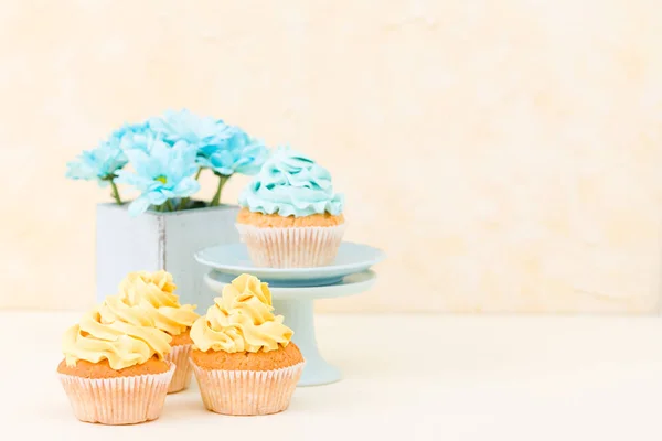 Cupcake with sweet blue and yellow buttercream decoration and blue chrysanthemum in retro shabby chic vase.