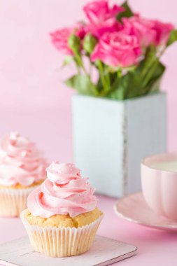 Pembe pastel dikey afiş ile dekore edilmiş cupcakes, sütlü kahve fincan ve pembe gül buketi.