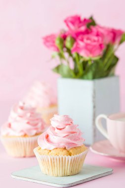 Pembe pastel dikey afiş ile dekore edilmiş cupcakes, sütlü kahve fincan ve pembe gül buketi.