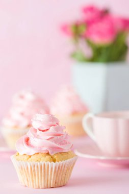 Pembe pastel dikey afiş ile dekore edilmiş cupcakes, sütlü kahve fincan ve pembe gül buketi.