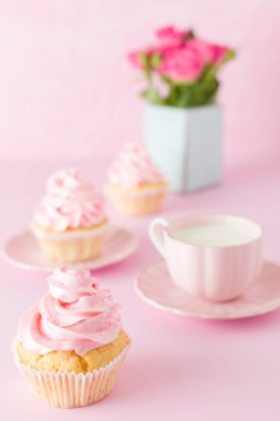 Pembe pastel dikey afiş ile dekore edilmiş cupcakes, sütlü kahve fincan ve pembe gül buketi.