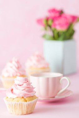 Pembe pastel dikey afiş ile dekore edilmiş cupcakes, sütlü kahve fincan ve pembe gül buketi.