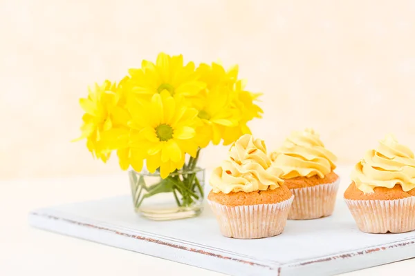 Cupcake com concurso decoração creme amarelo e buquê de crisântemo em vidro sobre fundo pastel amarelo . — Fotografia de Stock