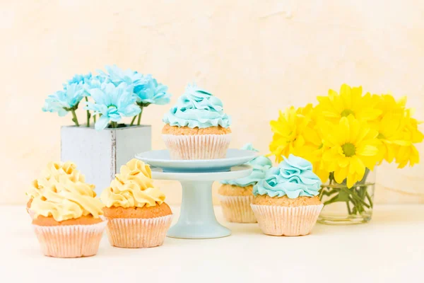 Crisântemo amarelo e azul em vaso chique gasto com cupcakes decorados com creme macio. Área de Copyscape — Fotografia de Stock