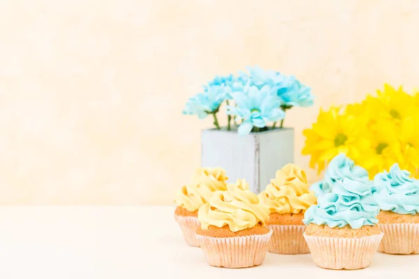 Crisântemo amarelo e azul em vaso chique gasto com cupcakes decorados com creme macio. Área de Copyscape — Fotografia de Stock