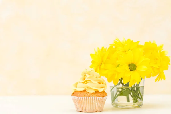 Cupcake com concurso decoração creme amarelo e buquê de crisântemo em vidro sobre fundo pastel amarelo . — Fotografia de Stock