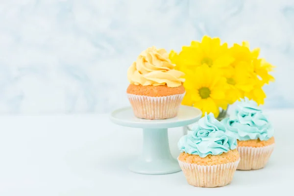 甜黄色奶油装饰的蛋糕和黄色菊花花束在复古破旧别致的花瓶在蓝色粉彩背景. — 图库照片