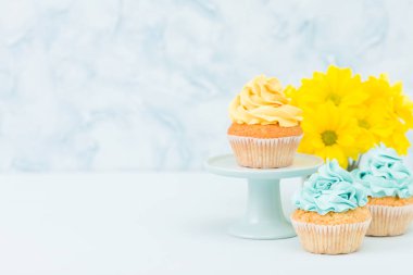 Tatlı sarı krem dekorasyon ve pastel mavi zemin üzerine retro eski püskü şık vazoda sarı Kasımpatı buket cupcake.