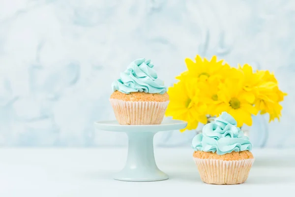 Cupcake com decoração creme amarelo no estande vintage e buquê de crisântemo amarelo em vaso de óculos . — Fotografia de Stock