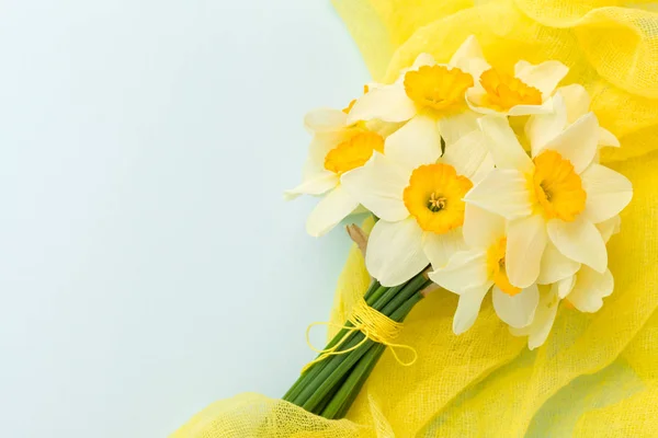 Buquê de daffodil com decoração têxtil amarela em fundo pastel azul com espaço de cópia . — Fotografia de Stock