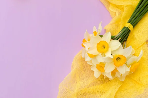 Buquê de daffodil com decoração têxtil amarela em fundo pastel violeta com espaço de cópia . — Fotografia de Stock