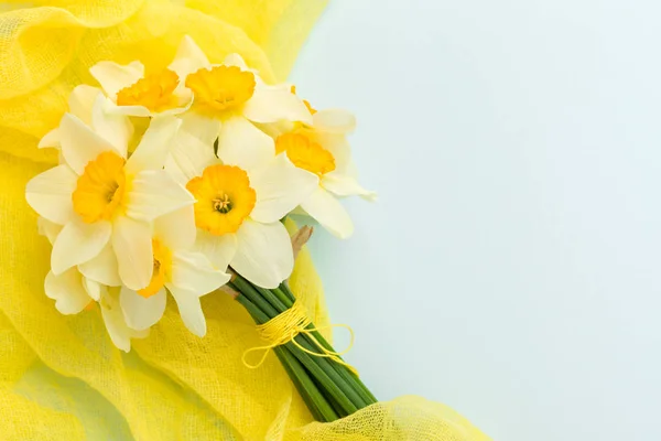 Buquê de daffodil com decoração têxtil amarela em fundo pastel azul com espaço de cópia . — Fotografia de Stock