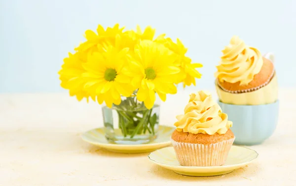 Cupcake com decoração de creme amarelo e buquê de crisântemo amarelo em vidro sobre fundo pastel concurso . — Fotografia de Stock