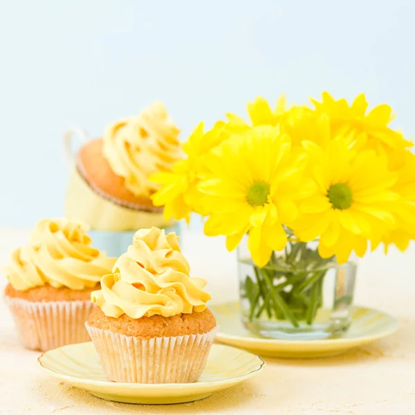 Cupcake com decoração de creme amarelo e buquê de crisântemo amarelo em vidro sobre fundo pastel concurso . — Fotografia de Stock