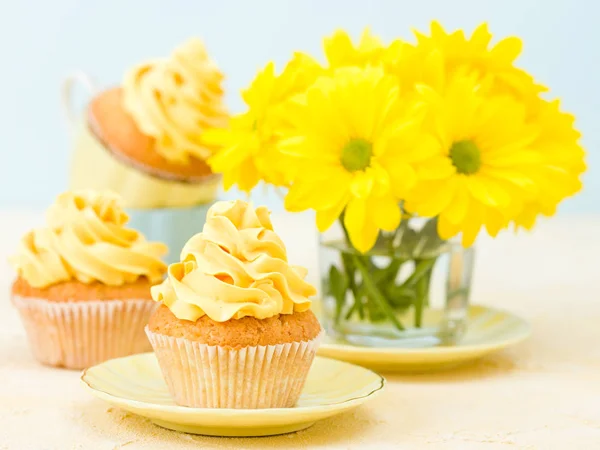 Cupcake com decoração de creme amarelo e buquê de crisântemo amarelo em vidro sobre fundo pastel concurso . — Fotografia de Stock