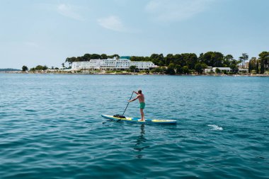 Adam açık güneşli bir günde denizde kürek çekmeye ayağa