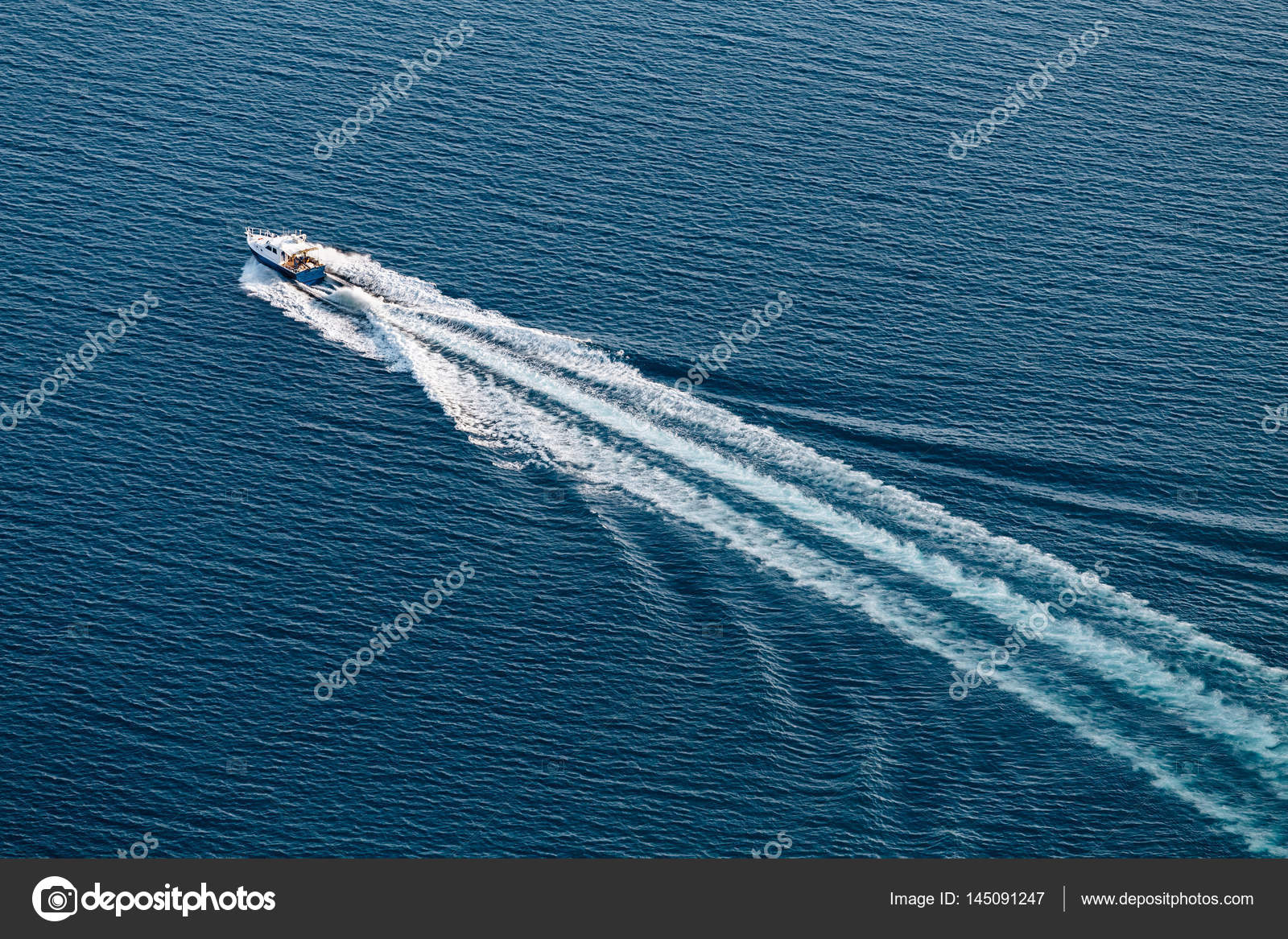 Top view of a small boat floating in the sea and creates a white waves