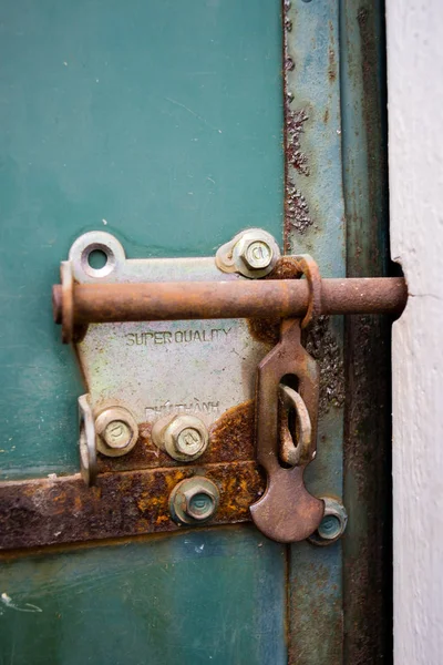 Fermo in acciaio arrugginito vecchio dettaglio porta verde — Foto Stock