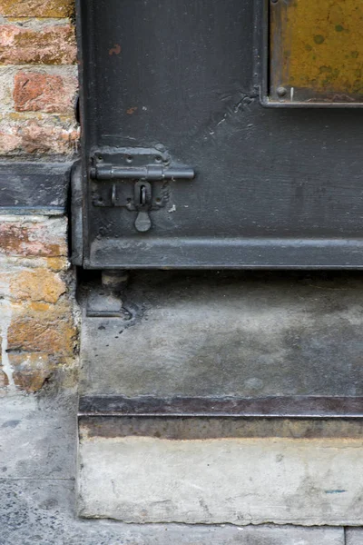 El pestillo de la puerta de acero en la puerta de acero rústico negro al lado de bric desnudo —  Fotos de Stock