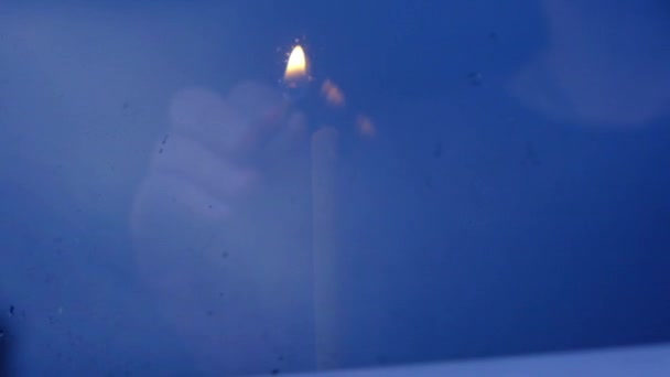 un homme allume une bougie. Main fermer la vue par la fenêtre, la nuit. Pâques à la maison . 