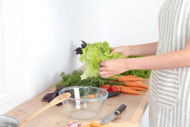 Mutfakta sebze doğrayan genç bir kadın.