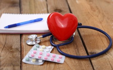 Kalp üzerinde ahşap arka plan izole bir stetoskop ile