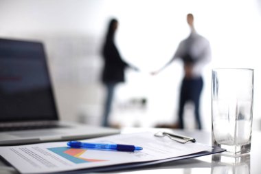 Dizüstü bilgisayar ile ağıl üstünde okul sırası, arka planda duran iki iş adamları