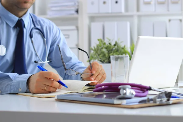 Mężczyzna lekarz za pomocą laptopa, siedzi przy biurku — Zdjęcie stockowe