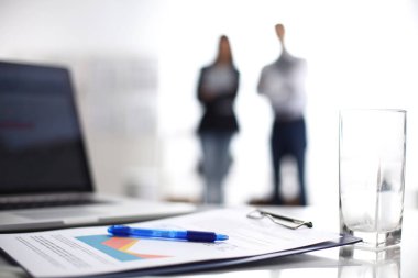 Dizüstü bilgisayar ile ağıl üstünde okul sırası, arka planda duran iki iş adamları