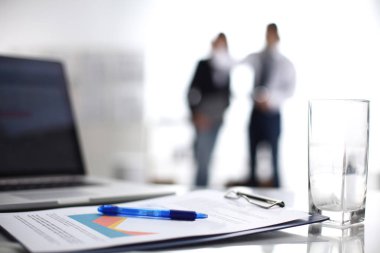 Dizüstü bilgisayar ile ağıl üstünde okul sırası, arka planda duran iki iş adamları