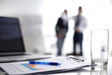 Dizüstü bilgisayar ile ağıl üstünde okul sırası, arka planda duran iki iş adamları