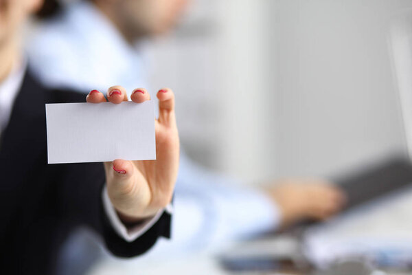 Бизнесмен показывает чистую карточку, сидя на столе
