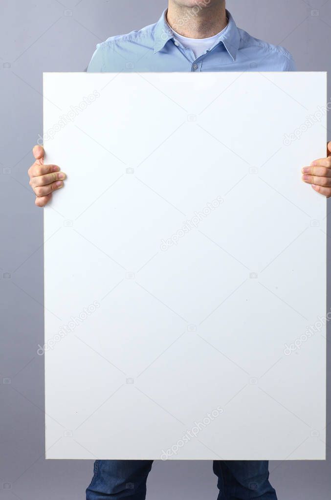Businessman holding a blank board on gray background