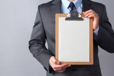 Ayakta gri arka plan üzerinde izole klasörle genç adam