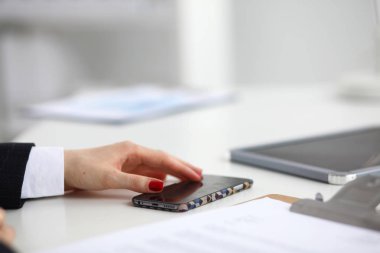 Masada oturan ofis telefonunu kullanarak iş kadını