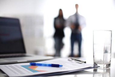 Dizüstü bilgisayar ile ağıl üstünde okul sırası, arka planda duran iki iş adamları