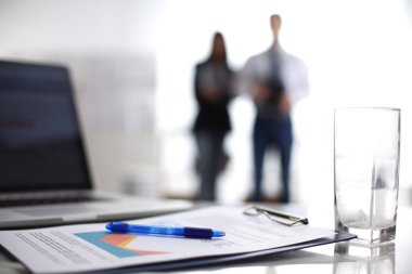 Dizüstü bilgisayar ile ağıl üstünde okul sırası, arka planda duran iki iş adamları