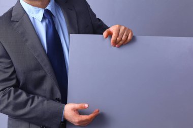 Genç işadamı gri arka plan üzerinde duran bir pano, holding