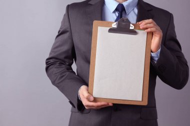 Genç işadamı gri arka plan üzerinde izole klasörle ayakta