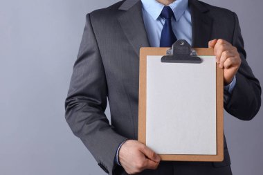 Ayakta gri arka plan üzerinde izole klasörle genç adam