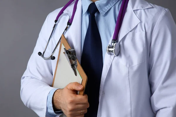 El médico con una bata blanca con un estetoscopio médico sosteniendo una carpeta — Foto de Stock