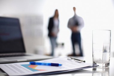 Dizüstü bilgisayar ile ağıl üstünde okul sırası, arka planda duran iki iş adamları