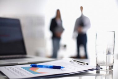 Dizüstü bilgisayar ile ağıl üstünde okul sırası, arka planda duran iki iş adamları