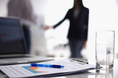 Dizüstü bilgisayar ile ağıl üstünde okul sırası, arka planda duran iki iş adamları