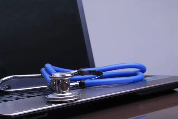 A medical stethoscope near a laptop on a wooden table — Stock Photo, Image