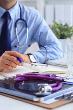 Erkek doktor ile sağlık stetoskop masasında oturan bir dizüstü bilgisayar kullanarak