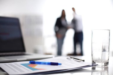 Dizüstü bilgisayar ile ağıl üstünde okul sırası, arka planda duran iki iş adamları