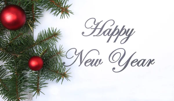 Texto feliz año nuevo en papel con árbol de piel, ramas, bolas de vidrio de colores, decoración y conos sobre un fondo de madera — Foto de Stock